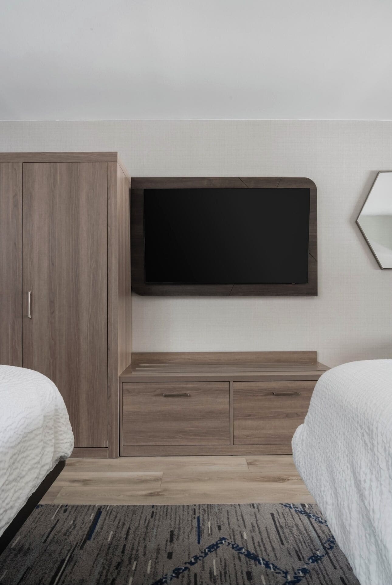 A hotel room with a bed, a wardrobe, a TV, and a small cabinet.