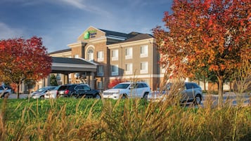 A Holiday Inn Express building with a brick facade, multiple windows, and a parking lot with several cars.
