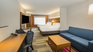 Een hotelkamer met een bed, een bureau met stoel, een bank, een televisie en een raam.