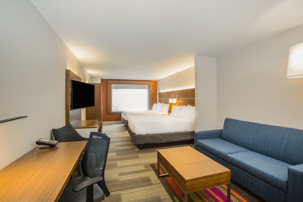Habitación de hotel con cama, escritorio, sillón, televisión y ventana.