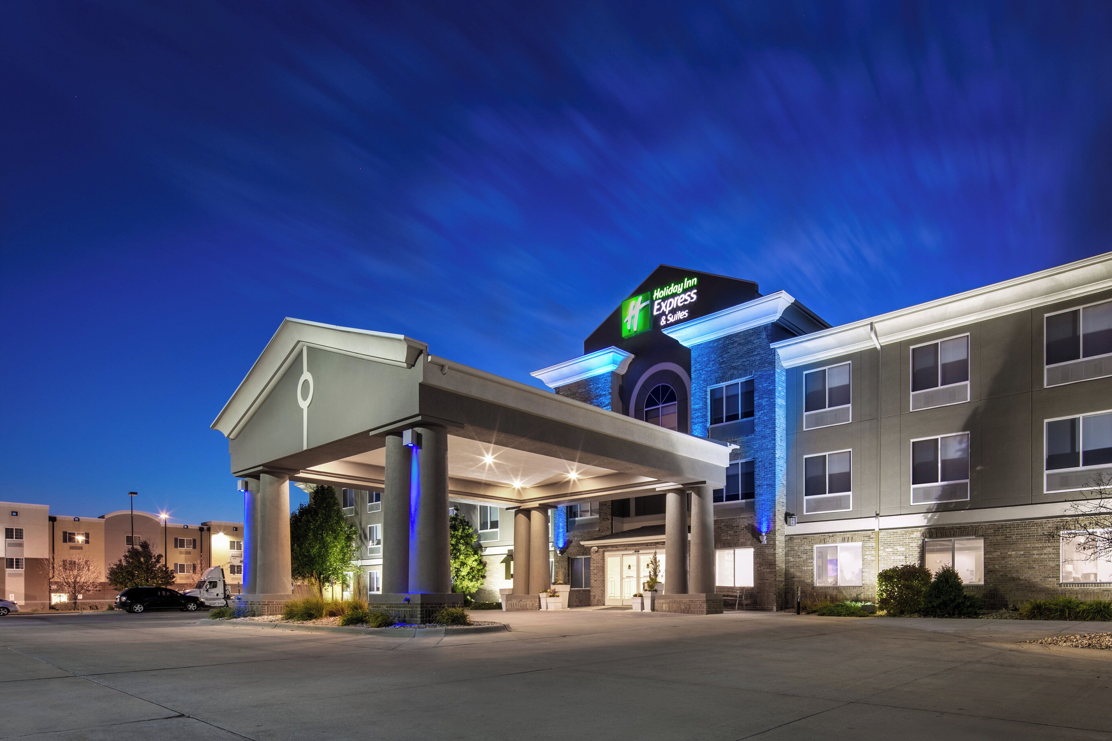 Un bâtiment Holiday Inn Express & Suites doté d’un espace extérieur couvert et d’un parking.