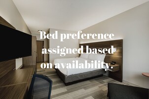 Una habitación de hotel moderna con cama, escritorio, televisor y mesita de noche.