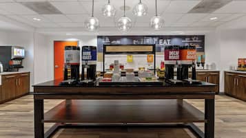 A breakfast area with a coffee machine, hot water dispenser, and a sign that says "HAPPY BREAKFAST STARTS HERE".