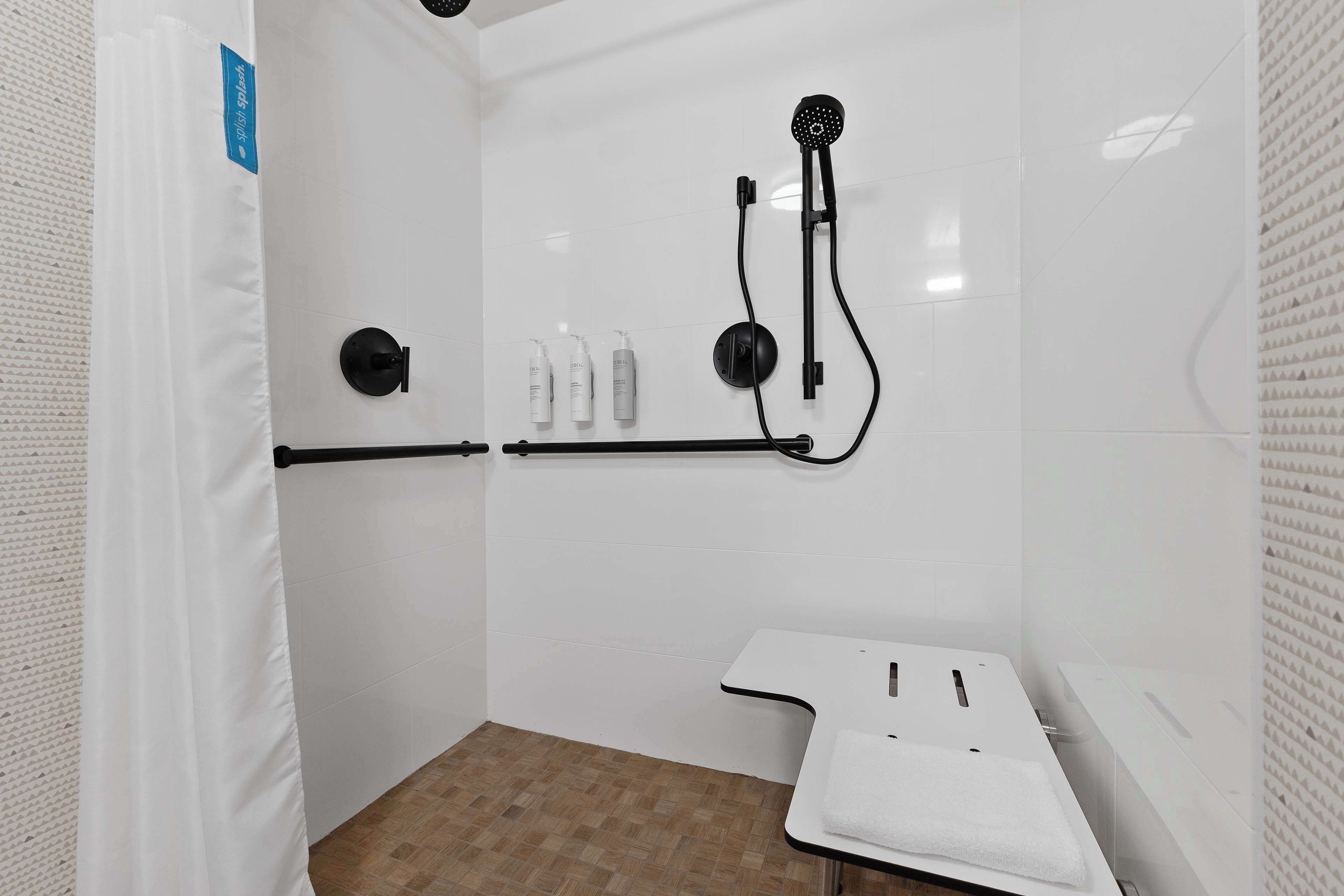 Un baño moderno con ducha, perchero y estante con artículos de aseo.