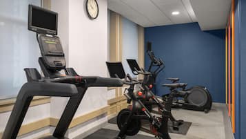 A fitness room with treadmills, an elliptical, and a stationary bike, equipped with digital displays.
