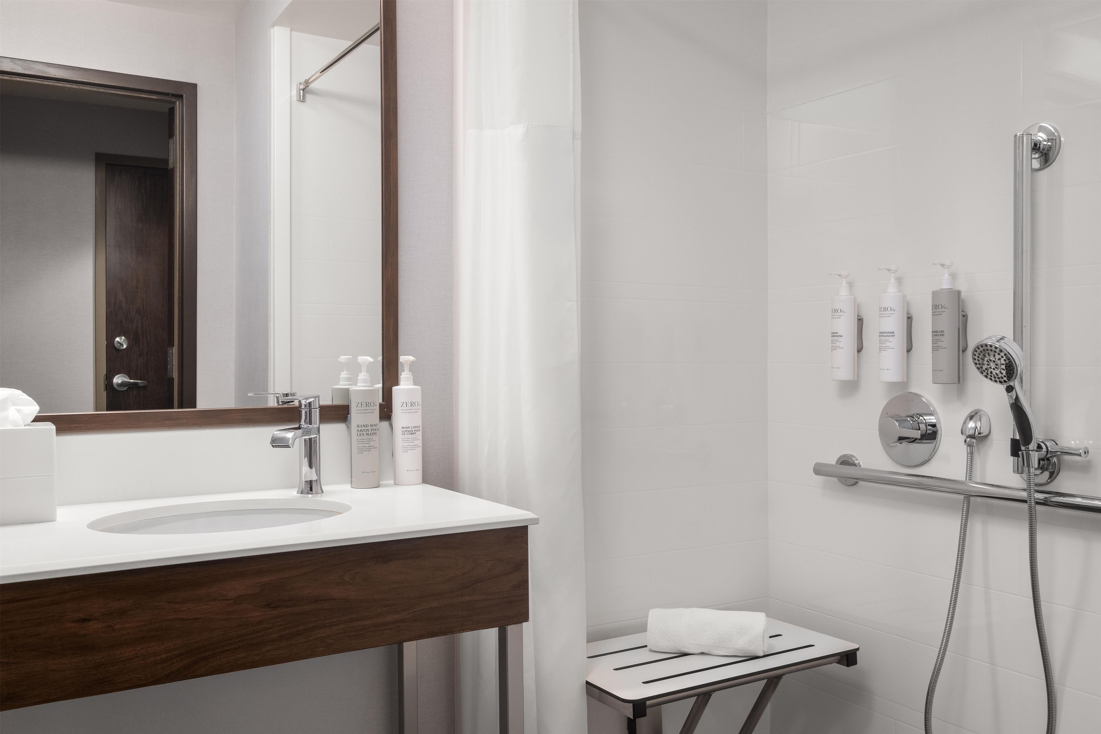 A modern bathroom with a white sink, a mirror, and a shower area.