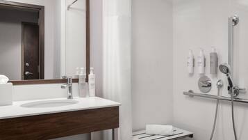 A modern bathroom with a white sink, a mirror, and a shower area.