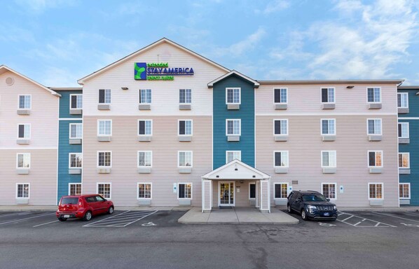 A multi-story hotel with a central entrance and parking lot. - Extended Stay America Select Suites - Fayetteville - Cliffdale (Fayetteville)