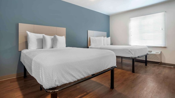 Two single beds with headboards, a window with blinds, and a wooden floor. - Extended Stay America Select Suites - Pensacola - Northeast (Pensacola)