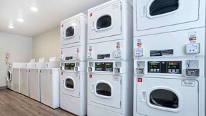 A row of stacked front-loading washers with digital displays and payment card slots. - Extended Stay America Select Suites - Pensacola - Northeast (Pensacola)