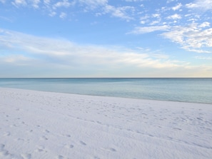 A beach with white sand and a calm sea under a partly cloudy sky. - Island Echos Condominiums (Fort Walton Beach)