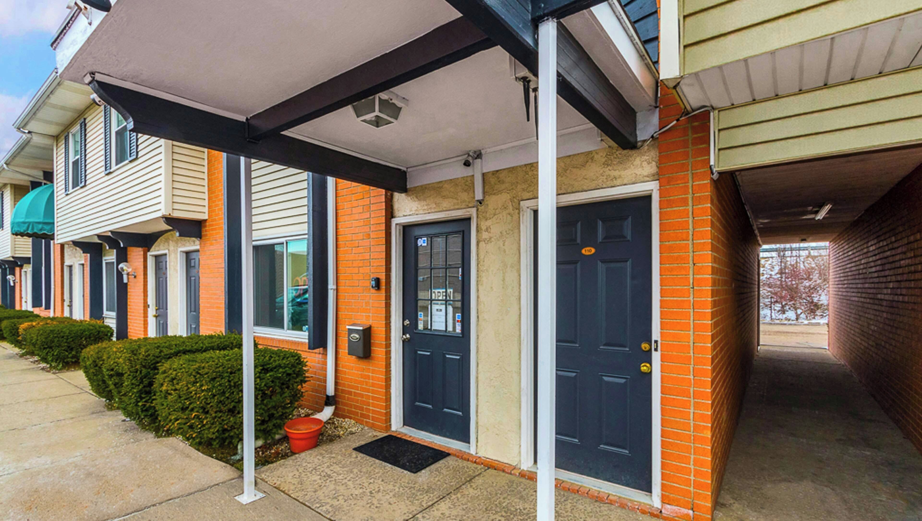 A townhouse with a covered porch, a black front door, and a brick facade.