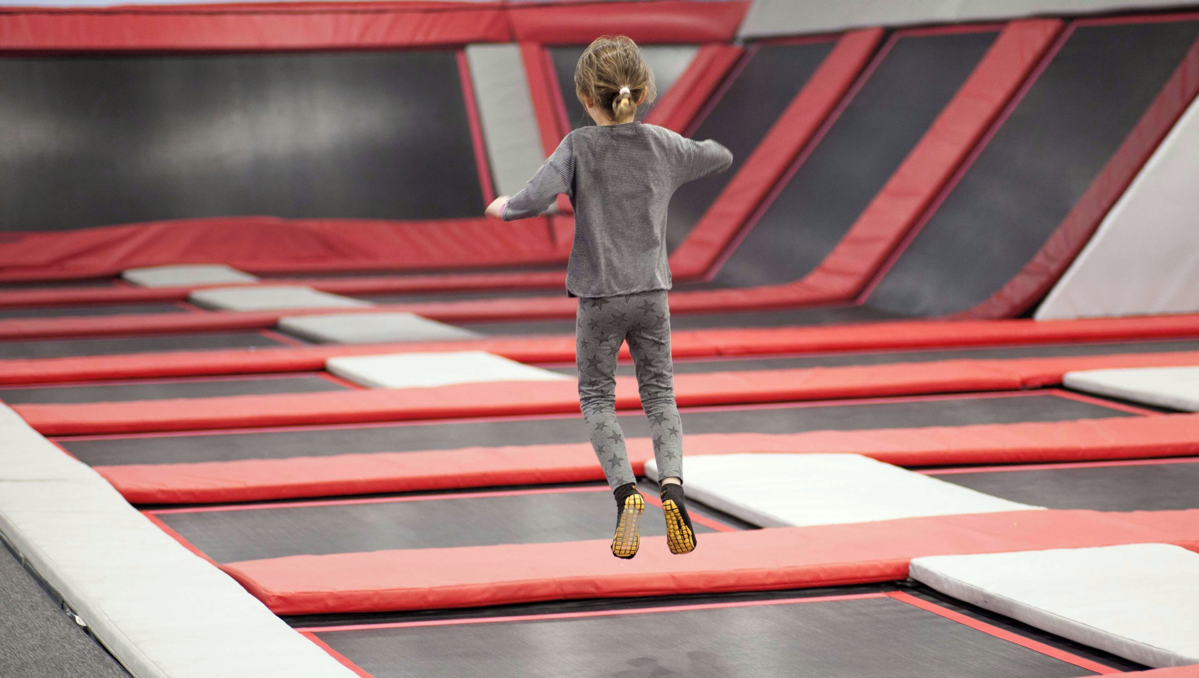 Ein Kind springt auf einem Trampolin mit mehreren Ebenen und gepolsterten Plattformen.