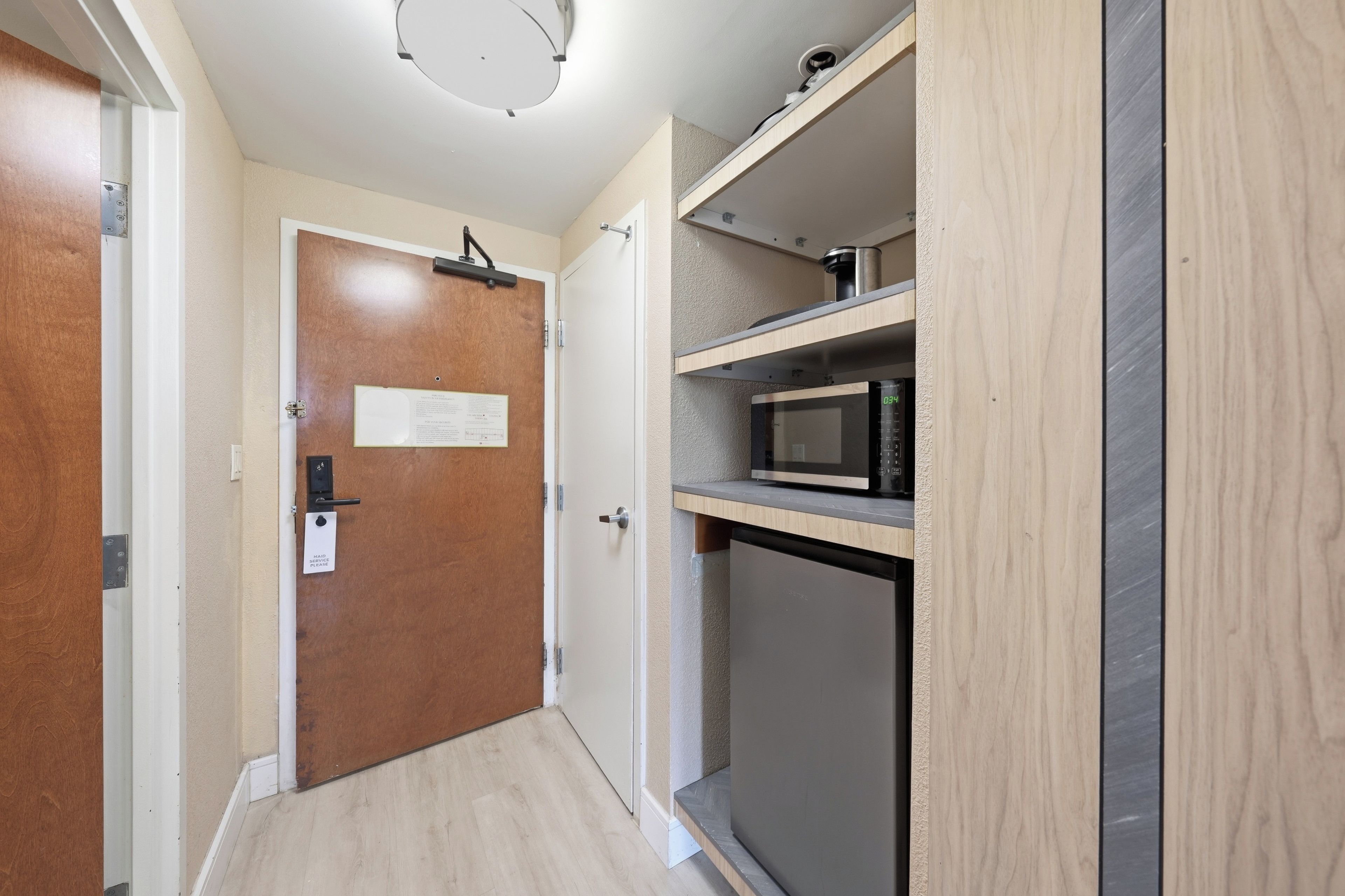 Una cocina compacta con microondas, un refrigerador pequeño y un mueble de madera.