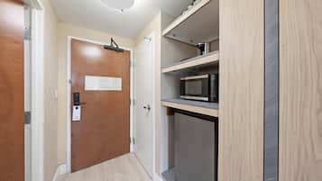 Una cocina compacta con microondas, un refrigerador pequeño y un mueble de madera.