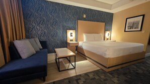 A hotel room with a bed, a sofa, a small table, and two bedside lamps. - Hotel Executive Suites Newark Liberty Int'l Airport Carteret (EWR) (Carteret)