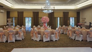 A banquet hall with round tables, white chairs, and pink floral centerpieces. - Hotel Executive Suites Newark Liberty Int'l Airport Carteret (EWR) (Carteret)