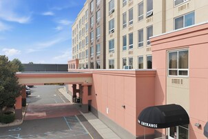A multi-story hotel entrance with a covered walkway, parking lot, and a sign indicating a 12-foot clearance.