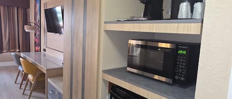 A modern kitchen with a microwave, coffee maker, and dishwasher. There is a dining area with a table and chairs.
