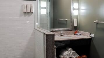 A modern bathroom with a glass-enclosed shower, a marble sink, and a built-in towel rack.