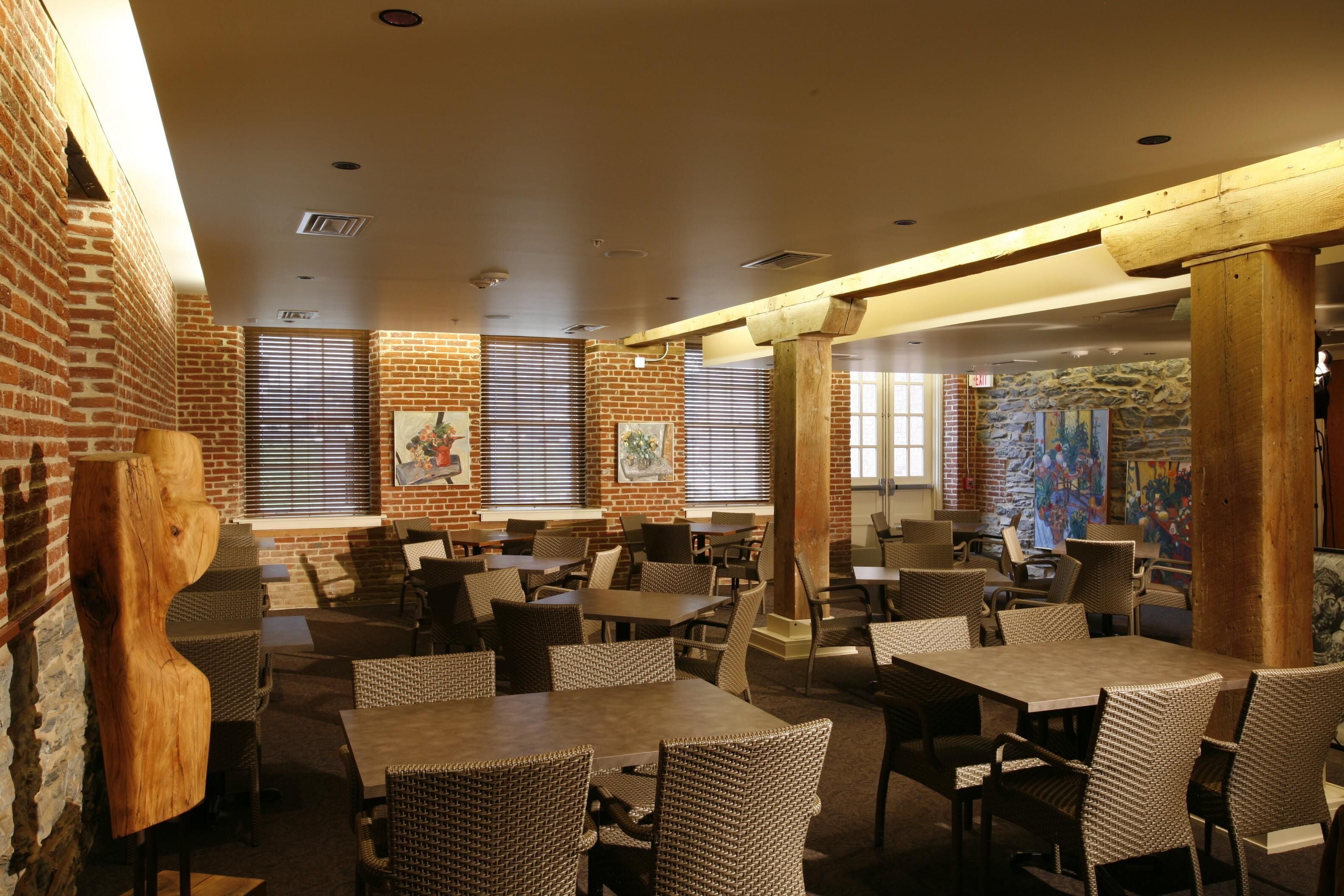 A restaurant with brick walls, wooden beams, and wicker furniture.