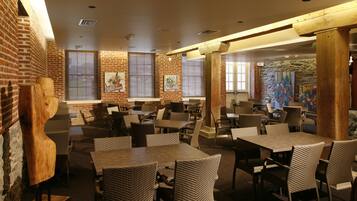 A restaurant with brick walls, wooden beams, and wicker furniture.