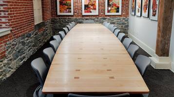Une salle de conférence avec une longue table, des chaises grises et des œuvres d’art accrochées aux murs.