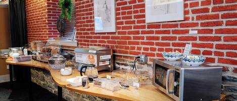 Un bar de cuisine avec une machine à café, un grille-pain et un four à micro-ondes, le tout installé devant un mur de briques orné d’œuvres d’art.