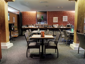Guests can dine in comfort with a table and chairs for groups, a counter with food and a microwave, and a carpeted floor.