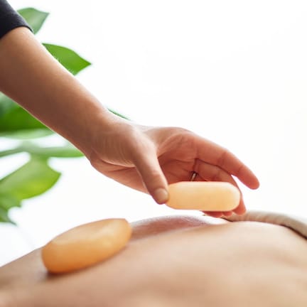 A hand applying a massage oil to a person's back.