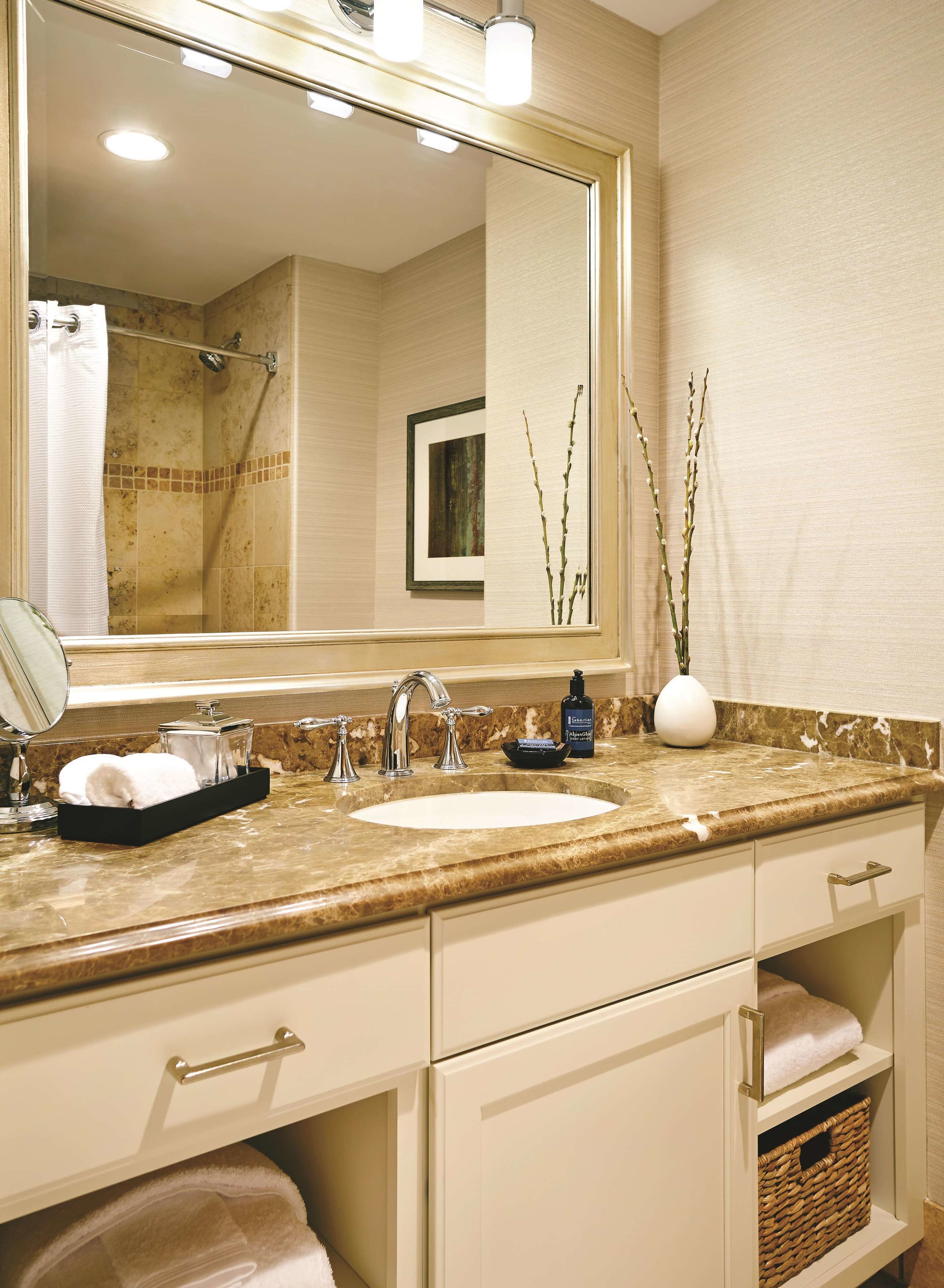 A bathroom with a sink, mirror, and towel rack.