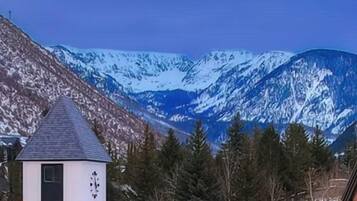 Un edificio con techo nevado y un campanario, rodeado de montañas cubiertas de nieve.