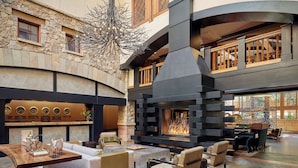 A spacious lobby with a stone fireplace, comfortable seating, and a clock display.