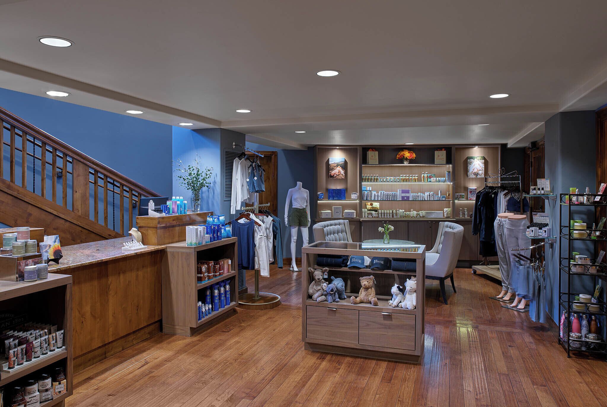 A boutique hotel lobby with wooden floors, a reception desk, a seating area, and a display of toiletries.