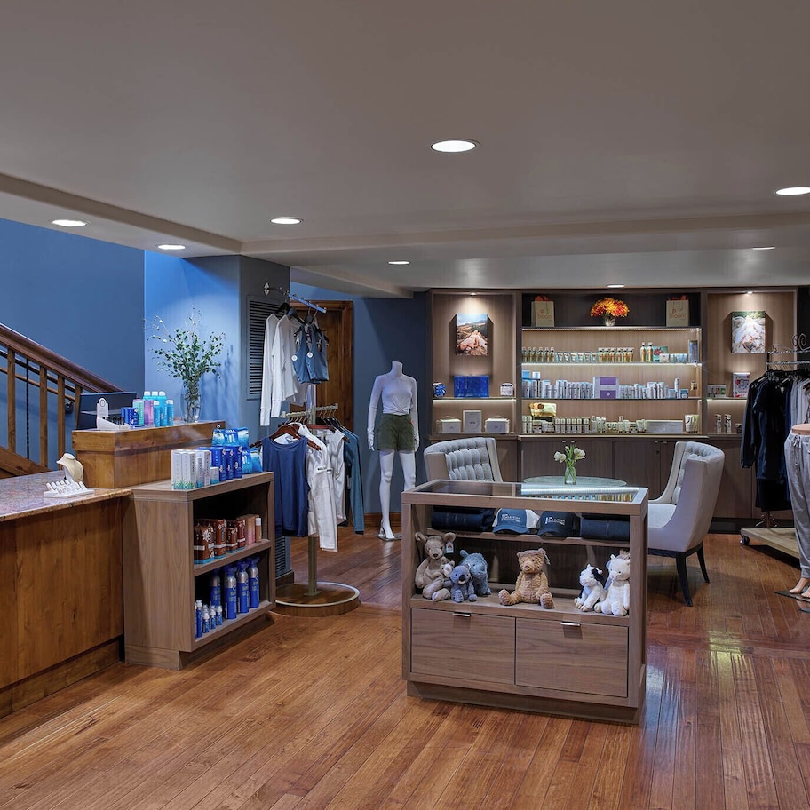 A boutique hotel lobby with wooden floors, a reception desk, a seating area, and a display of toiletries.