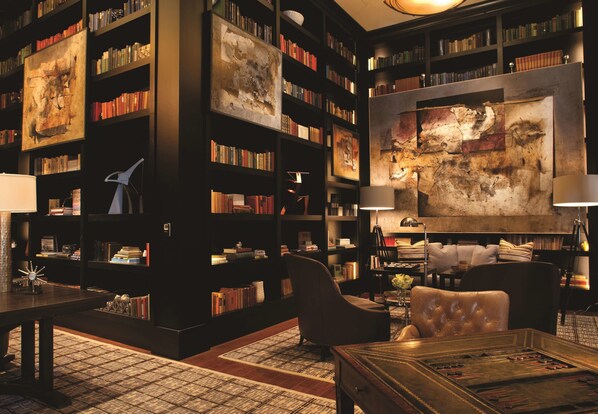 Una biblioteca con estanterías, un cuadro abstracto de gran tamaño y sillones de cuero.