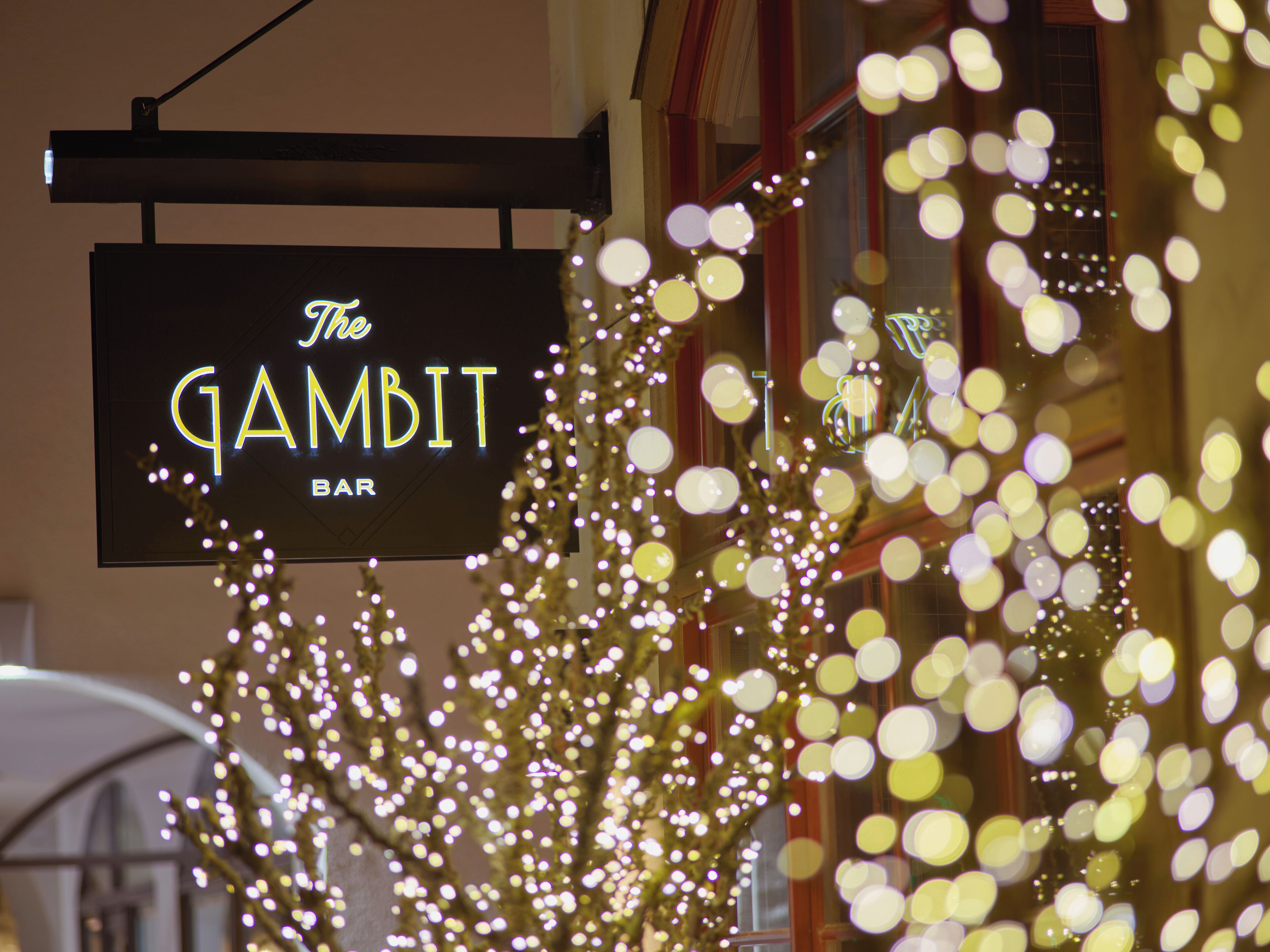 Un cartello per 'The GAMBIT BAR' con luci decorative in primo piano.