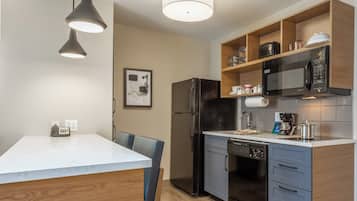 A modern kitchen with a central island, a refrigerator, a microwave, and a coffee maker.