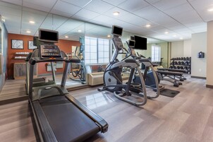 Un gimnasio con cintas de correr, elípticas y bancos de pesas.