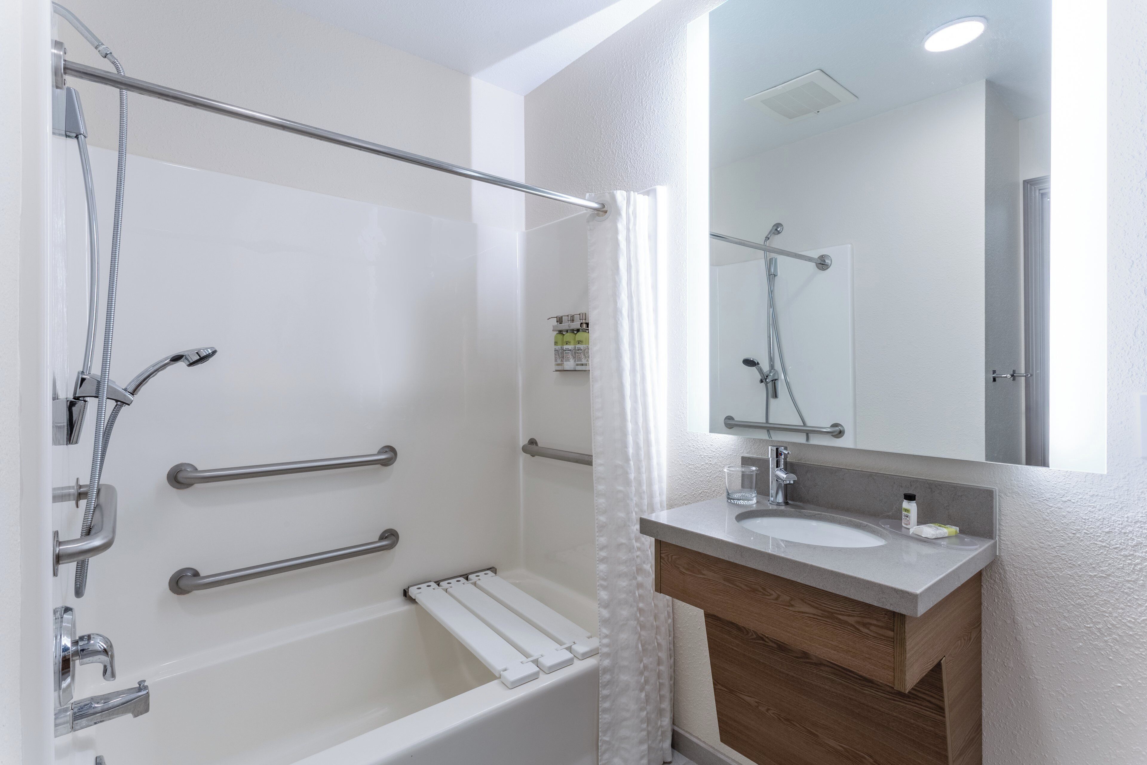 A modern bathroom with a bathtub, shower, and vanity.
