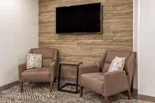 Una habitación con dos sillones, una mesita auxiliar y un televisor de pantalla plana montado en una pared de madera.