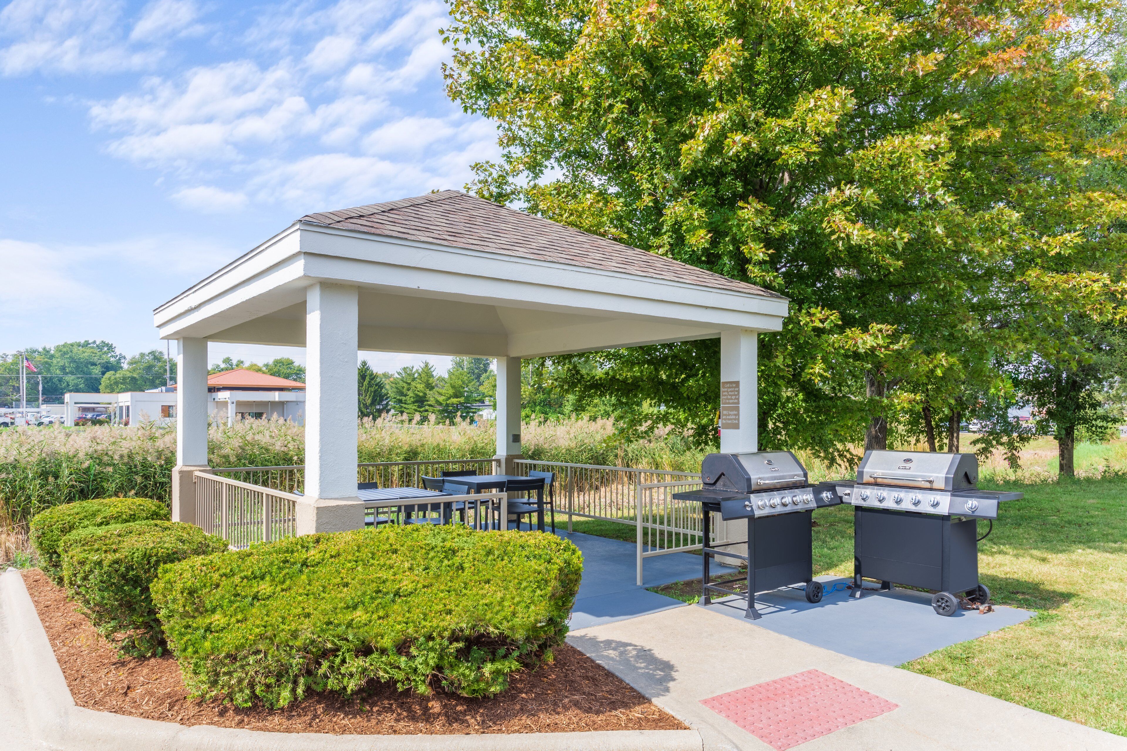 A covered outdoor area with a barbecue station and seating.