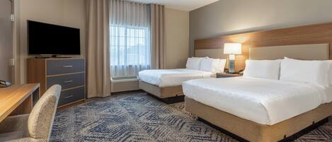 A hotel room with two beds, a TV, a desk, and a chair.