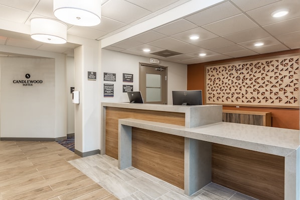 A reception desk with a modern design, a sign for Candlewood Suites, and a patterned wall. - Candlewood Suites O Fallon by IHG (O'Fallon)