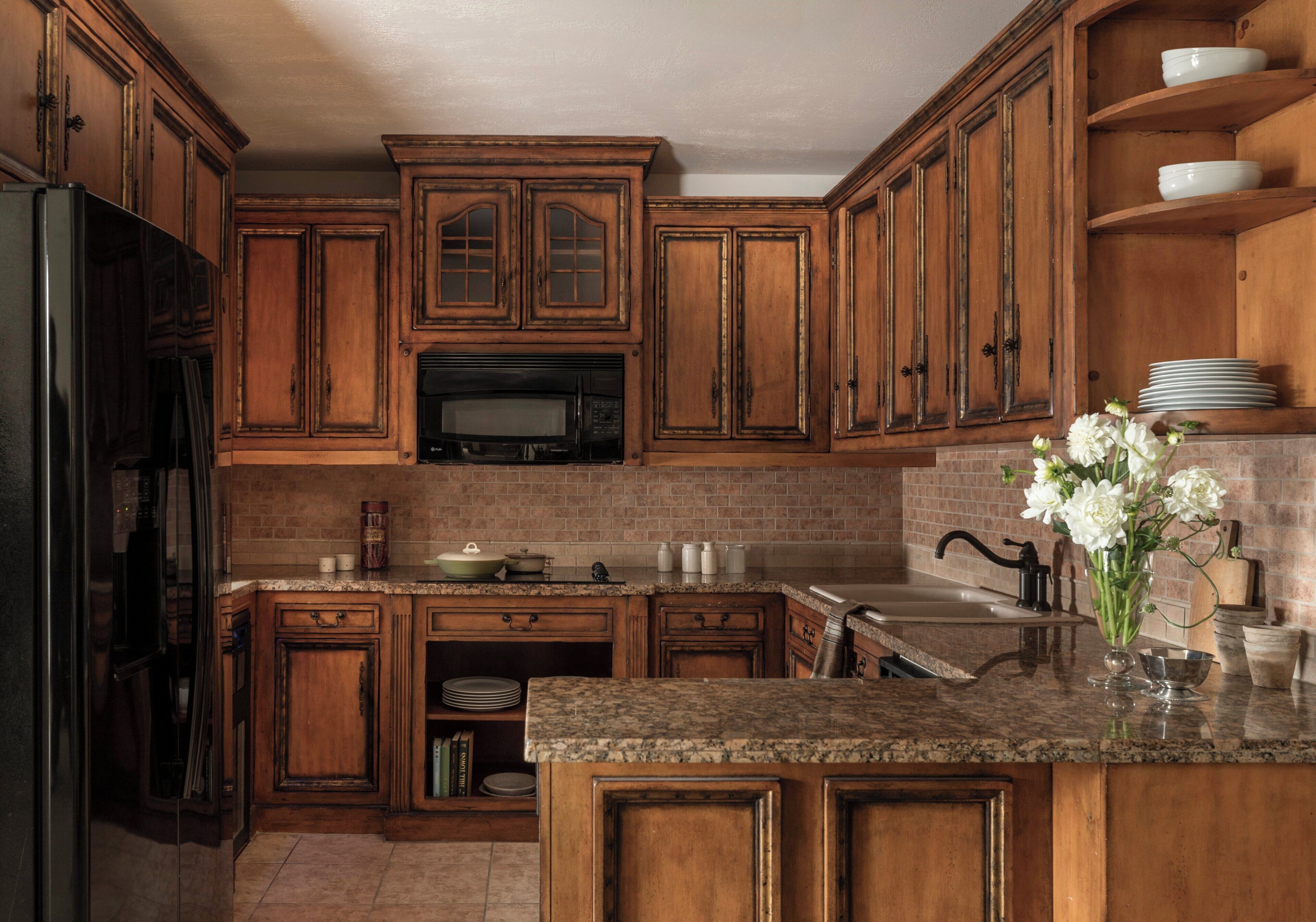 A kitchen with wooden cabinets, a granite countertop, a stainless steel sink, and a microwave.