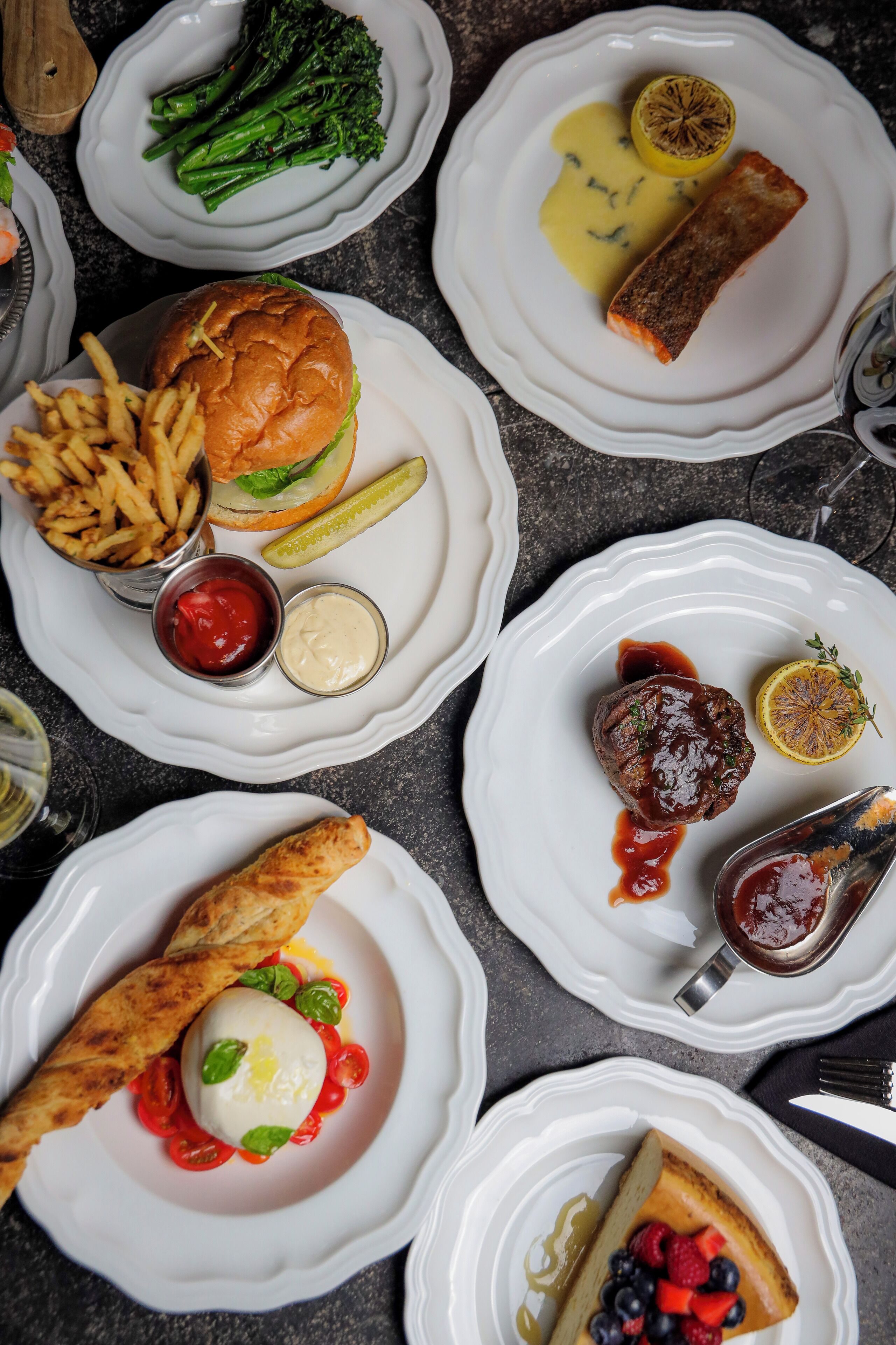Variedad de platos en blanco, incluyendo pescado, una hamburguesa y un postre.