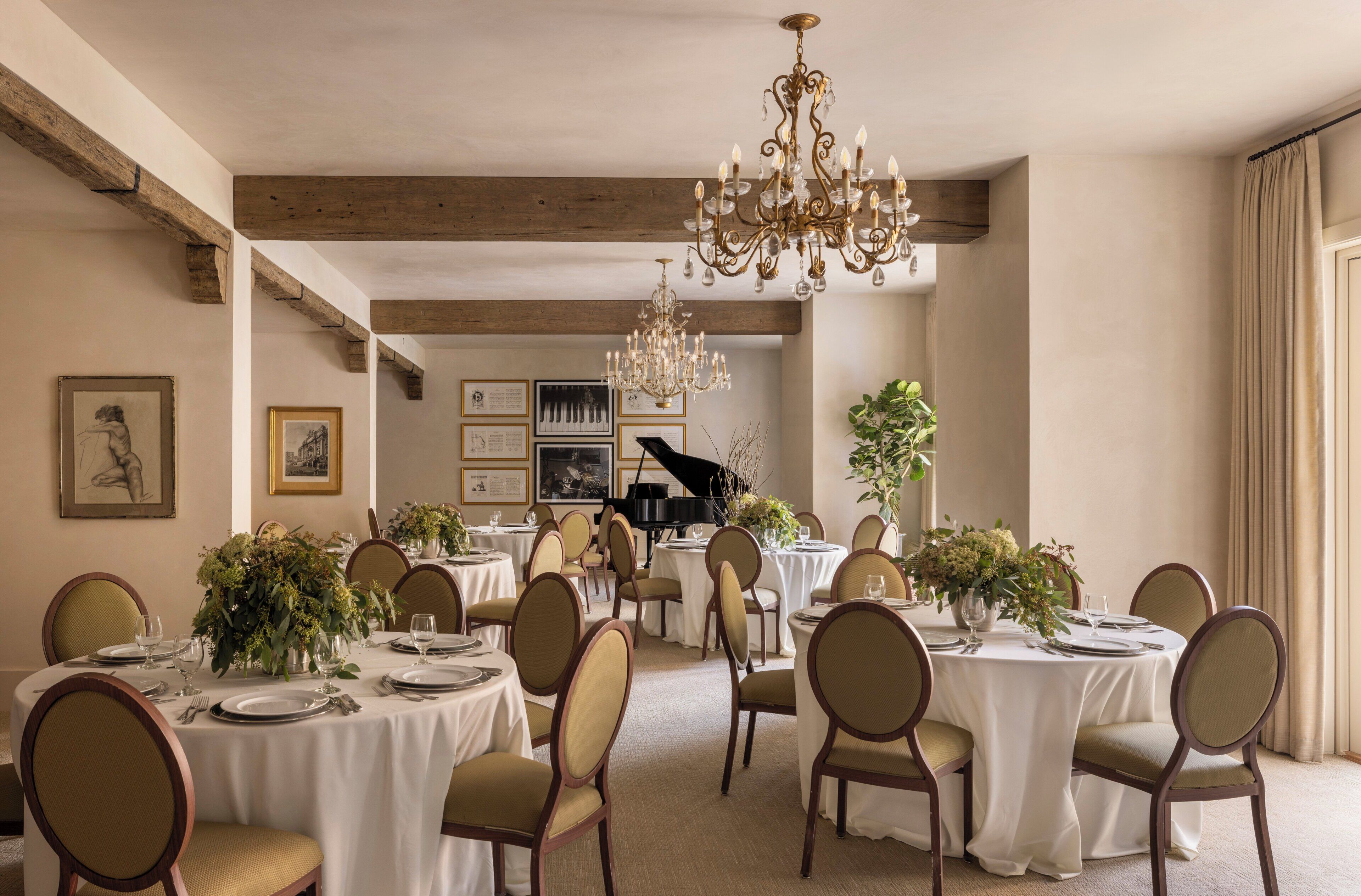 A formal dining room with round tables, chairs, and a grand piano in the background.