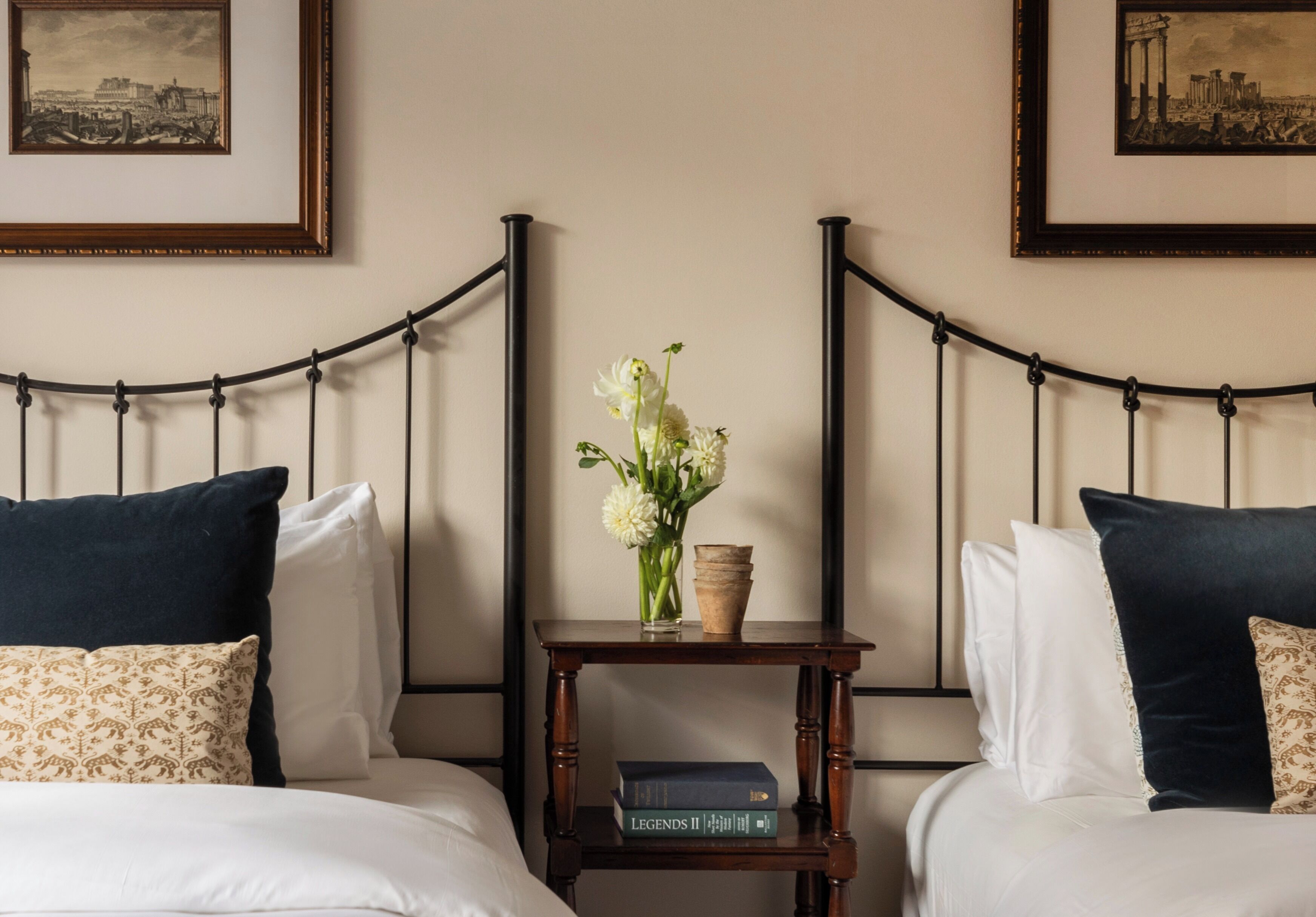 Une chambre d’hôtel avec un lit, une table de chevet ornée d’un vase de fleurs et des tableaux encadrés accrochés au mur.
