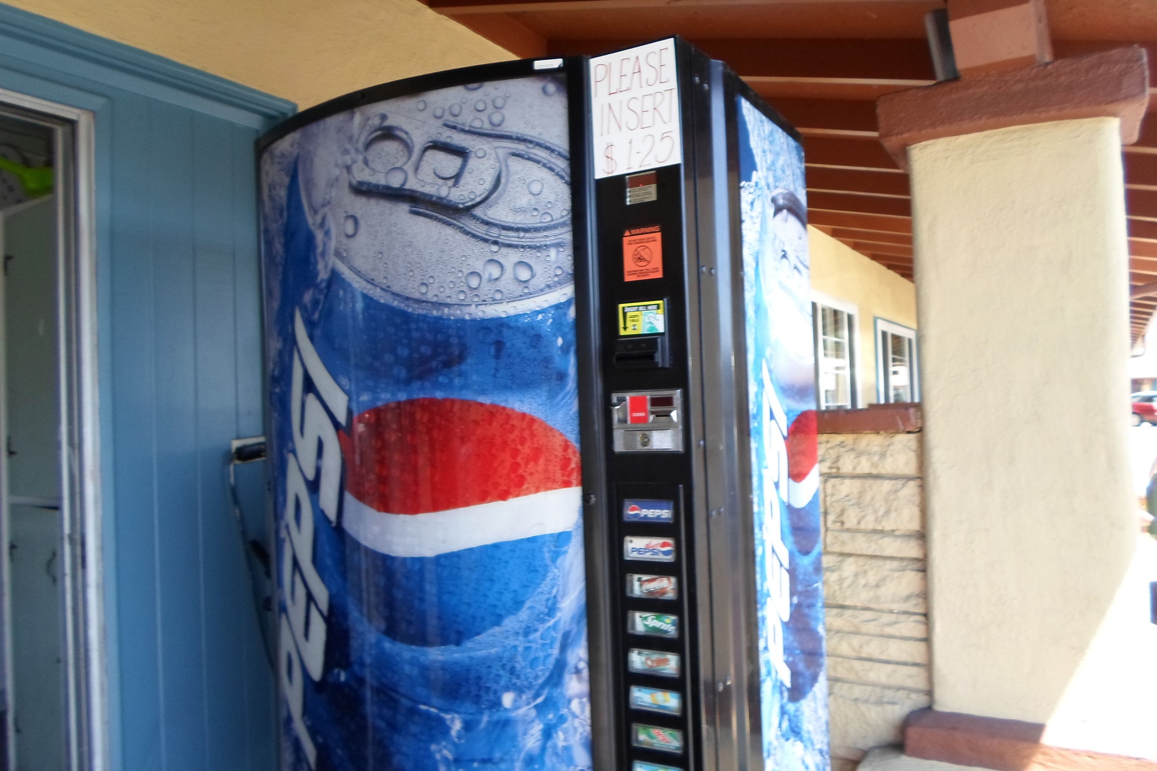 Una máquina expendedora con el logotipo de Pepsi, una ranura de pago y un letrero que indica insertar dinero.