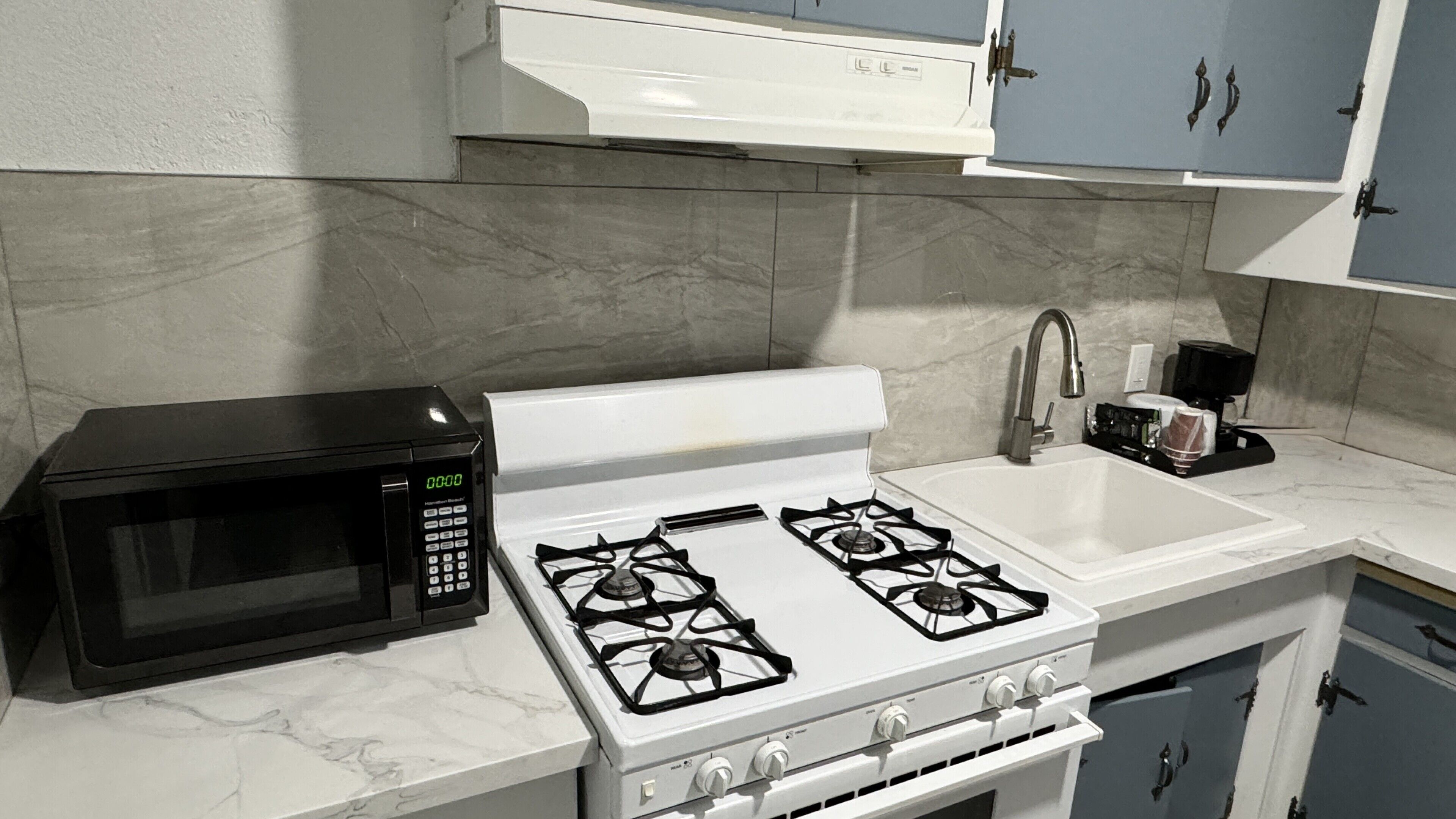 A kitchen with a microwave, stove, sink, and cabinets.